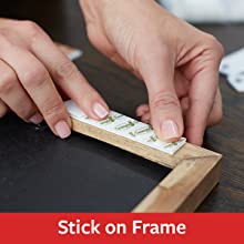 hands applying command picture hanging strips to the back of a frame