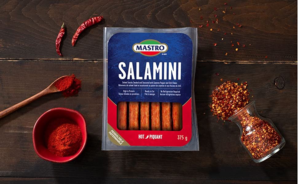 Package of Mastro Salamini Hot on a table with chili peppers and spoon with spices