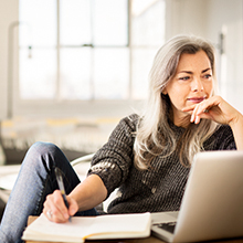 Woman at home in front of her laptop; Always Discreet are designed for bladder leaks.